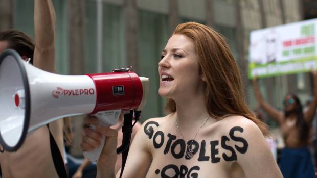 $!Rachel Jessee speaks into a megaphone while riding atop a car during the GoTopless Day Parade, Sunday, Aug. 23, 2015, in New York. The parade, organized by the women's advocacy group GoTopless, was meant to promote equality for women by calling attention to women's right to go bare-chested in public. (AP Photo/Kevin Hagen)