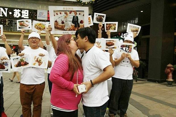 $!Pic shows: The couple kissing. A jealous boyfriend deliberately fattened up his girlfriend to put off any love rivals. Businessman You Pan, 25, met pretty Yan Tai, 20, when she only weighed just over seven stone. But after he took her out regularly for big breakfasts, lunches and dinners she ballooned in weight to a massive 14 stones. And just to be sure no one else took any interest in her, he even woke her up and fed her midnight snacks. The unusual courtship has been happening in in South Chinas Guangdong Province and has been the talk of the town ever since it was reported in local media. The story came out when after two years of dating Tou proposed to Yan, 19, with a chocolate bouquet and a promise to love her and feed her even more. She said yes and when she posted the images online, revealed the reason for the chop okay which quickly became one of the most talked about discussions on Chinese social media platforms. Neighbour Yi Chiang who has known the girl since she was little said: Its hard to believe how much weight Yan has put on but she is still very beautiful. She will make a lovely bride and Im sure they will be very happy together. I dread to think how much they have spent on food but if it makes them happy then why not. (ends)